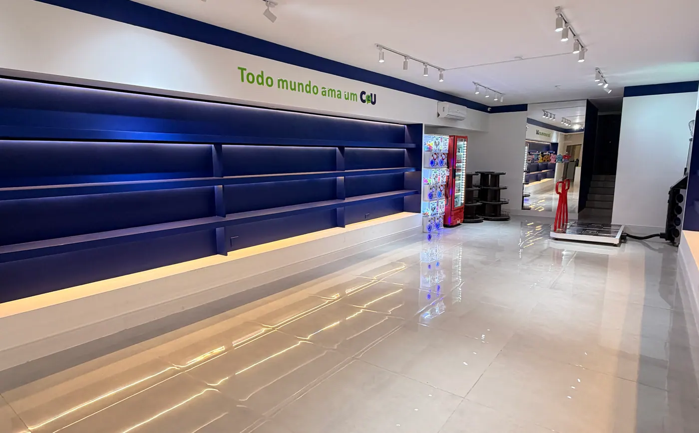 Salão da loja com gôndolas iluminadas e vitrine ao fundo