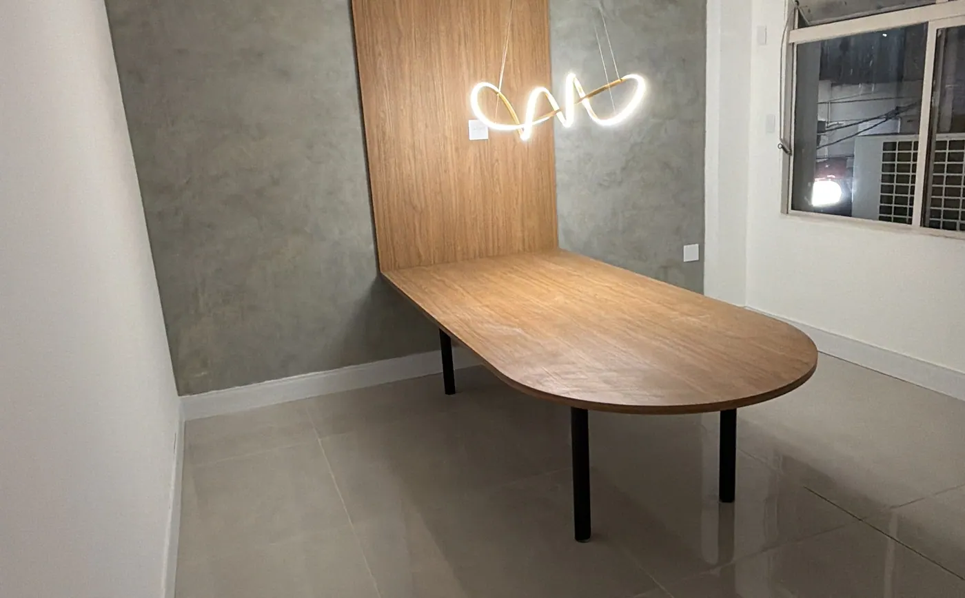 Sala comercial com ripado de madeira, mesa oval e luminária de neon